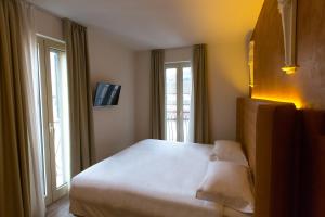 a bedroom with a large bed and two windows at Hotel Al Campanile - Luxury Suites & Apartments in Baveno