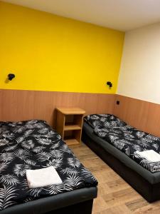 twee bedden in een kamer met een gele muur bij Penzion u Fika in Ostrava