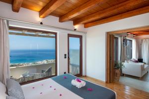 a bedroom with a large window with a view of the ocean at Stefanos Village Hotel in Plakias