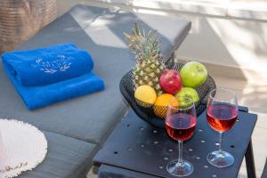 a bowl of fruit and two glasses of wine on a table at Stefanos Village Hotel in Plakias