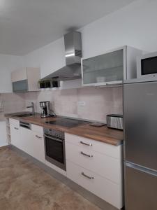 una cocina con armarios blancos y electrodomésticos de acero inoxidable en A FRAME 1 TRANSALPINA en Petreşti