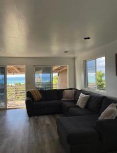 a living room with a black couch and windows at North Shore Vacation Home - Best Views in V Land ! in Haleiwa