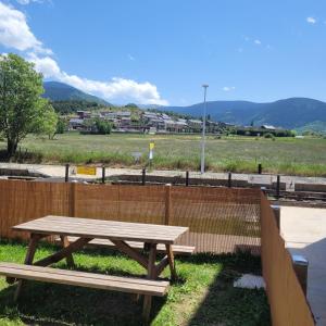 a wooden picnic table sitting next to a fence at Loft mansardé du train jaune avec vue sur les montagnes in Saillagouse