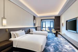 ein Hotelzimmer mit 2 Betten und einem Flachbild-TV in der Unterkunft voco Xiong'An in Baoding