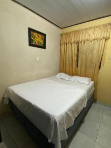 a bedroom with a white bed with a window at Hostal Yahuarcaca in Leticia