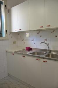 Una cocina con gabinetes blancos y un fregadero. en Villa Teti - Sicilia, en Campofelice di Roccella