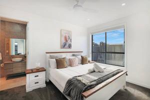 um quarto branco com uma cama grande e uma janela em Illalangi-Modern Escape & Views em Mudgee