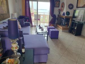 a living room with purple couches and a tv at Evi in Xylokastro