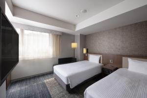 una camera d'albergo con due letti e una televisione di ibis Styles Kyoto Shijo a Kyoto