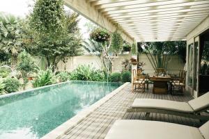 a swimming pool in a backyard with a table and chairs at Riverside French Villa in Thuan An