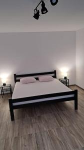 Schlafzimmer mit einem Bett mit weißer Bettwäsche und Holzböden in der Unterkunft Apartman Lapis Fructus in Pridraga