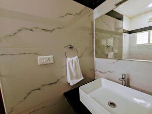 Baño blanco con lavabo y espejo en TPC Camphor en Tiruchchirāppalli