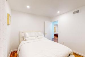 een witte slaapkamer met een bed met witte lakens en kussens bij Urban Flower in Sylmar
