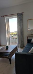 a living room with a couch and a table and a window at Faros Apartments in Xerokampos