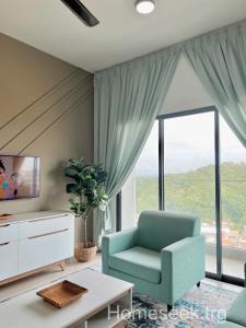 a living room with a blue chair and a large window at Homeseek, Spacious and Cozy Apartment in Kuala Terengganu in Kuala Terengganu