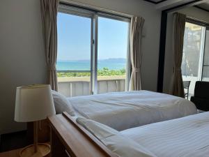a bedroom with a bed and a large window at Ocean Front SUMUIDE in Nago