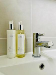 two bottles ofodorizers sitting on a bathroom sink at Cosy Coastal 2-Bedroom Cottage with Hot Tub and Log Burner in West Mersea