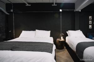 a bedroom with two beds and a black wall at Bedsment in Chiang Rai