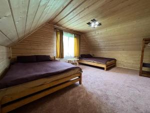 a bedroom with two beds in a log cabin at Котедж Mezohat in KozÊ¼meshchek