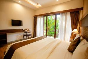 a bedroom with a large bed and a window at Ratan Uluwatu Hotel and Villas in Uluwatu