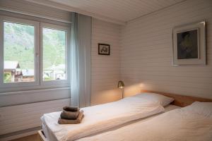 Schlafzimmer mit einem Bett und einem Fenster in der Unterkunft Chalet Tidu modern chic stylish in Zermatt