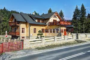 una casa de madera con una valla en el lateral de la carretera en Noclegi Styrnol & SPA, en Zawoja