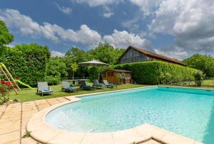 una piscina in un cortile con sedie e ombrellone di The cottage at Les Chouettes Tremolat a Trémolat