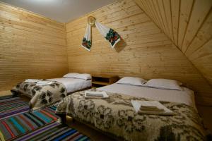 two beds in a room with wooden walls at Căsuța Doinița in Borşa
