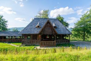 a log cabin with a black roof on a field at Căsuța Doinița in Borşa