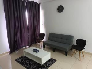 uma sala de estar com um sofá, uma mesa e cadeiras em Alanis Residence@KLIA em Sepang