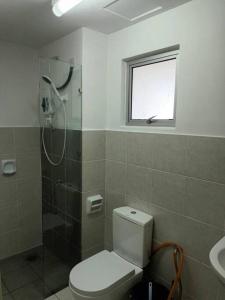 uma casa de banho com um WC, um chuveiro e uma janela. em Alanis Residence@KLIA em Sepang