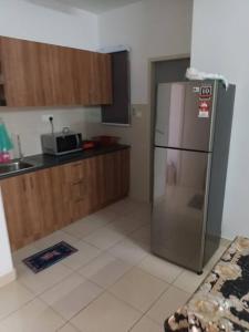 a kitchen with a stainless steel refrigerator and wooden cabinets at Alanis Residence@KLIA in Sepang