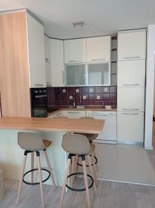 une cuisine avec des placards blancs et deux tabourets de bar dans l'établissement M&M Apartment, à Kotor