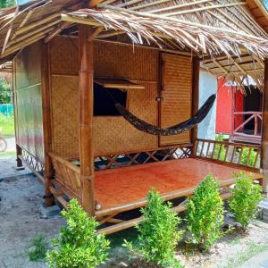 een bed in een huis met rieten dak en een hangmat bij New Andaman Bay Bungalow in Koh Lanta