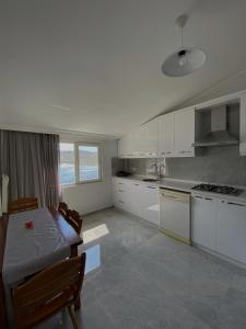 a kitchen with white cabinets and a table and a dining room at Melisa Hotel in Bozburun