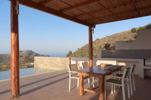 a wooden table and chairs on a patio with a view at Sunrise Villa, a Secluded Gem in South Crete, By ThinkVilla in Marioú