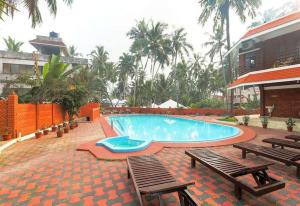 a swimming pool with two benches and a building at Hotel Moonlight, Kovalam, Kerala in Kovalam