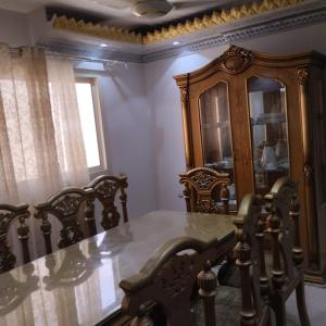 a dining room with a table and chairs and a cabinet at شقة مفروشة سوبر لوكس للايجار in Cairo