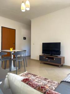 Il comprend un salon doté d'une télévision et d'une table avec des chaises. dans l'établissement Sunrise Golem Summer Apartment, à Durrës