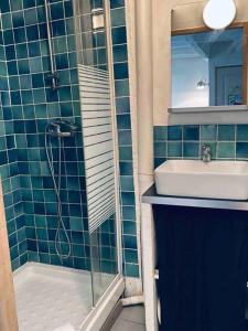 uma casa de banho em azulejos azuis com um lavatório e um chuveiro em Bienvenue chez vous au Panier ! Appartement classé 1 étoile em Marselha