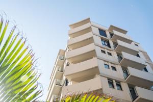 een hoog appartementencomplex met een palmboom bij Hotel Adonis Capital in Santa Cruz de Tenerife