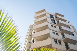 un edificio de apartamentos alto con una palmera en Hotel Adonis Capital, en Santa Cruz de Tenerife