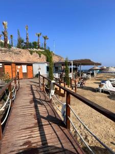 un paseo marítimo de madera que conduce a una playa con un complejo en Bodrum Gundogan Full Sea View With Garden Triplex Villa en Bodrum