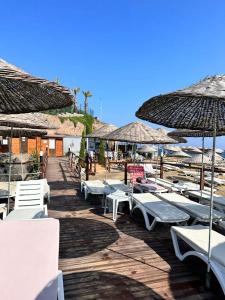 a row of lounge chairs and umbrellas on a beach at Bodrum Gundogan Full Sea View With Garden Triplex Villa in Bodrum City