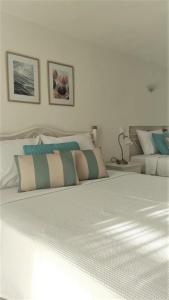 - une chambre dotée d'un lit blanc avec des oreillers bleus et verts dans l'établissement Pansion Katerina, à Ouranoupoli