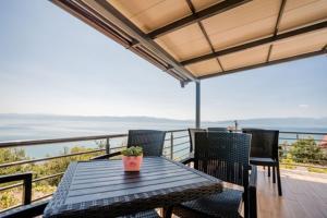 uma mesa e cadeiras numa varanda com vista para o oceano em VILA PUPA, Elešec 2 em Ohrid