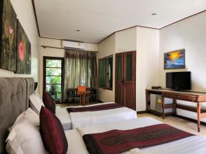 a hotel room with two beds and a desk at Baan Panwa Resort in Panwa Beach