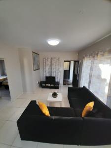 a living room with a black couch and yellow pillows at Margate Sunset Apartments in Margate