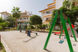 un parque infantil con un tobogán en la arena frente a un edificio en Calanova, en Mijas