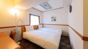 niewielka sypialnia z białym łóżkiem i oknem w obiekcie Toyoko Inn Gumma Ota eki Minami guchi w mieście Ota